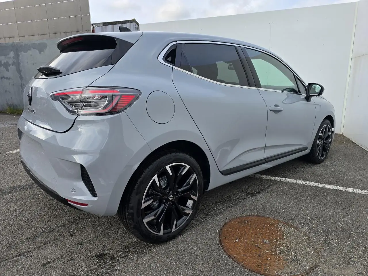 Vue 3/4 arrière droite d'une Renault Clio gris rafale métallisé avec jantes alliage noires et vitres surteintées.