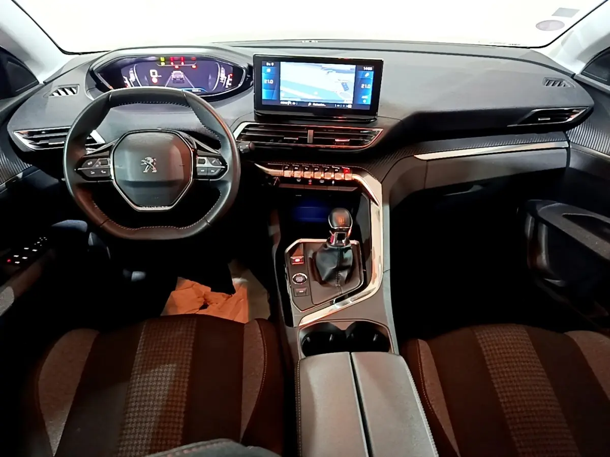 Vue intérieure avant du Peugeot 5008 noir 2021, tableau de bord avec écran tactile central et volant compact multifonctions.