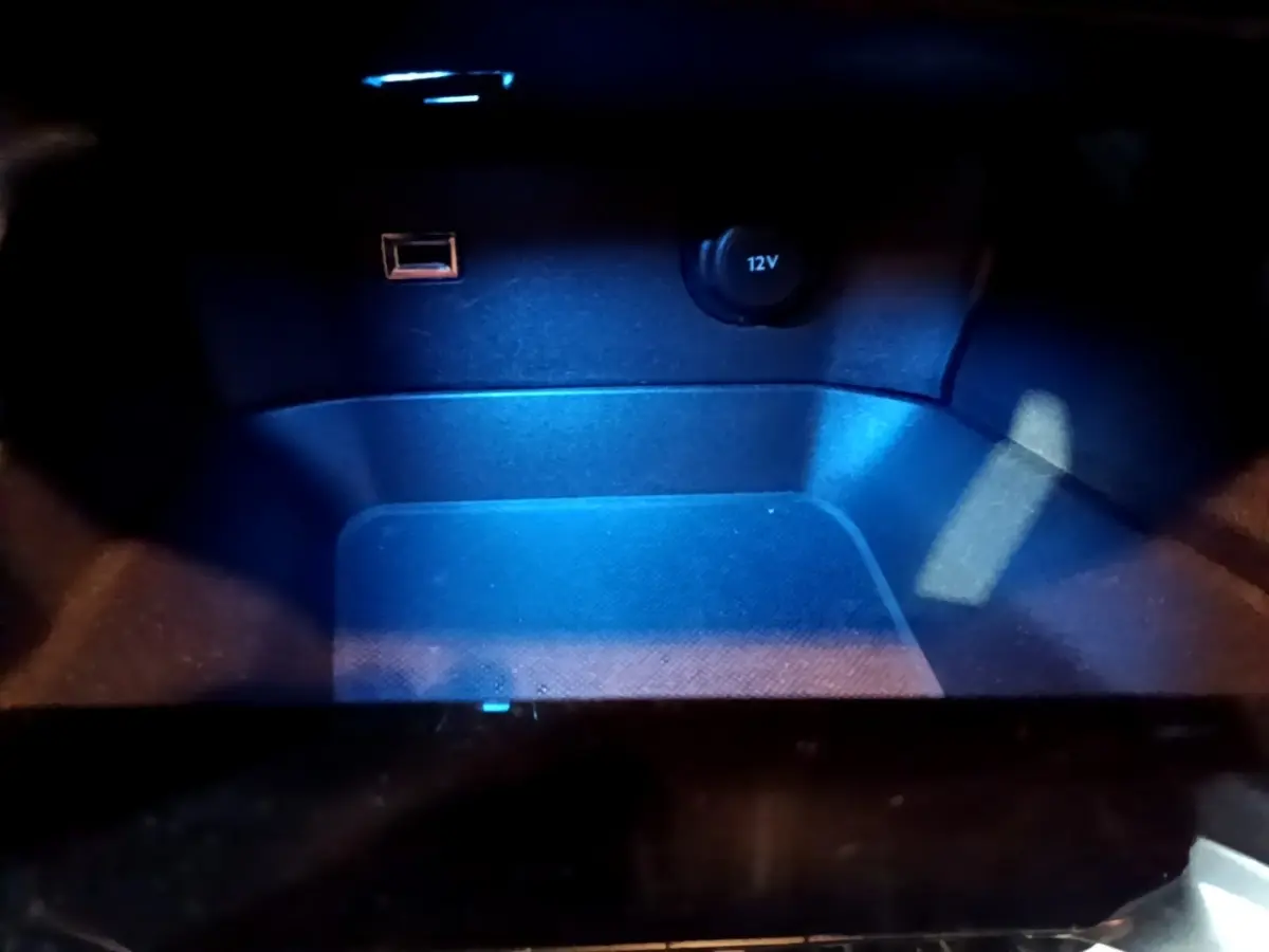 Gros plan sur la prise 12V et port USB éclairés en bleu dans le compartiment intérieur du Peugeot 5008 noir.