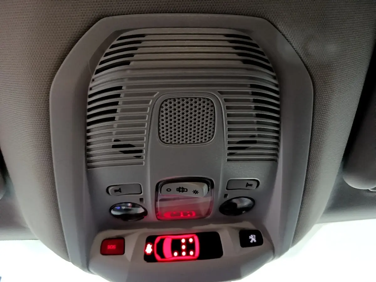Vue en contre-plongée du plafonnier intérieur gris du Peugeot 5008 noir, avec boutons lumineux et alerte SOS rouge.