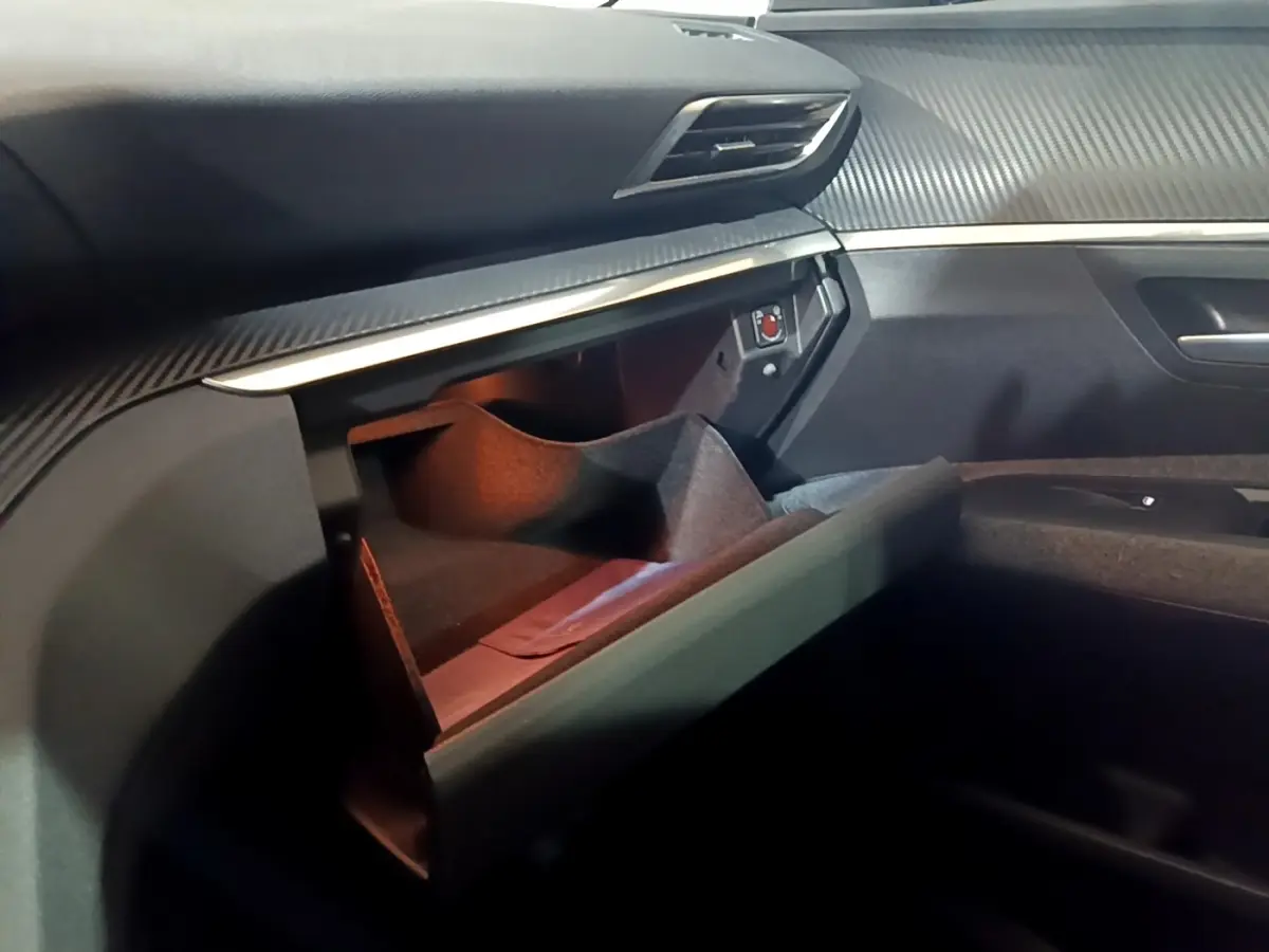 Intérieur Peugeot 5008 2021 noir, vue du rangement ouvert côté passager avec tableau de bord texturé.