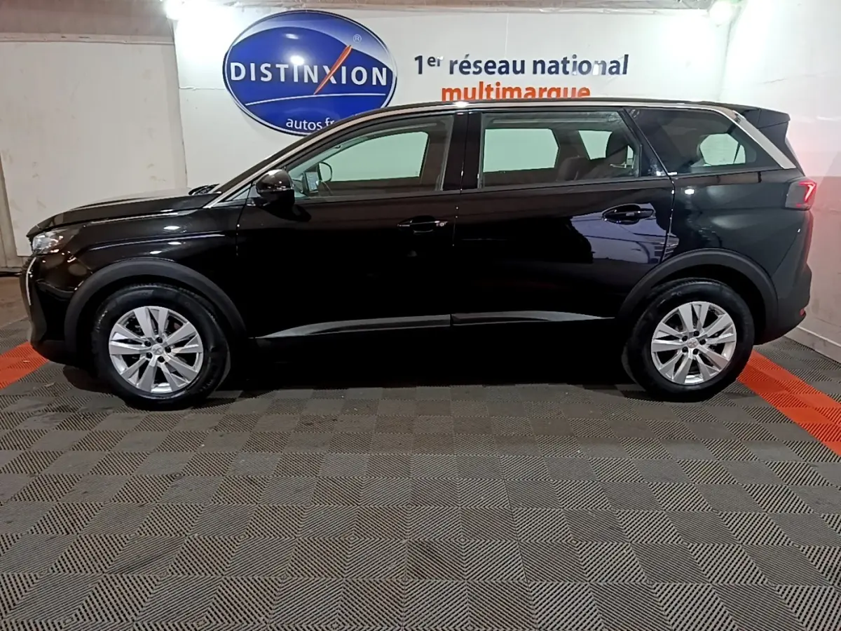 Peugeot 5008 noir vue de profil côté gauche dans un showroom avec jantes alliage et vitres teintées.