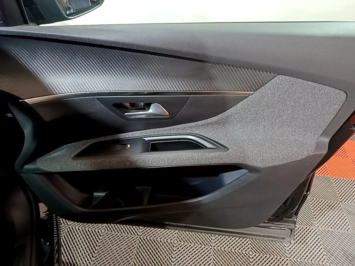 Vue rapprochée de la porte intérieure côté conducteur du Peugeot 5008 noir, avec garniture texturée et poignée métallique.