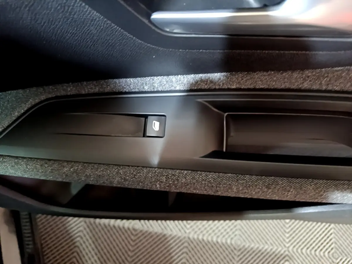Gros plan sur la commande de lève-vitre électrique intégrée dans la garniture de porte intérieure noire du Peugeot 5008.