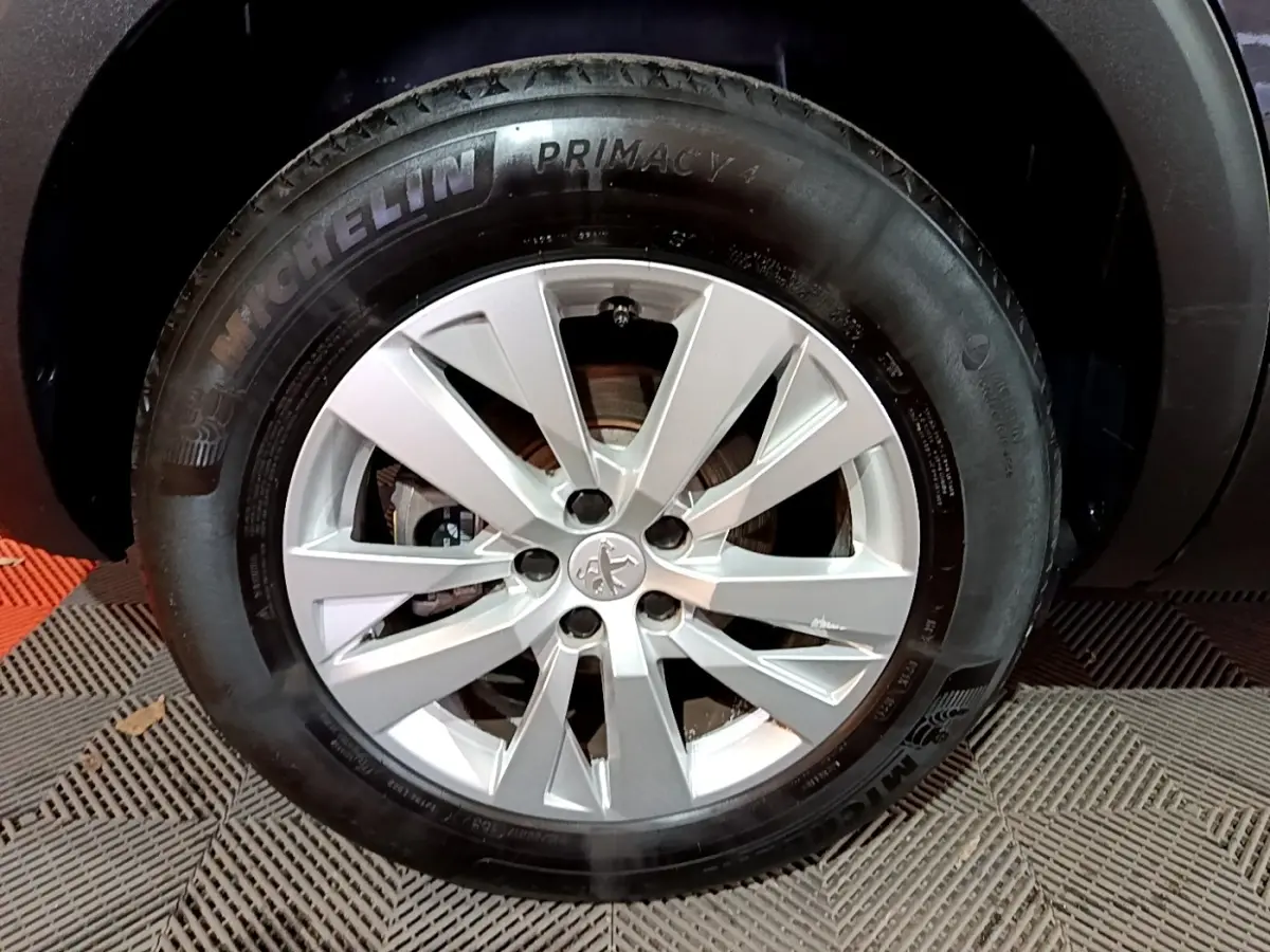 Gros plan sur la roue avant droite d’un Peugeot 5008 noir, avec jante argentée et pneu Michelin Primacy 4.
