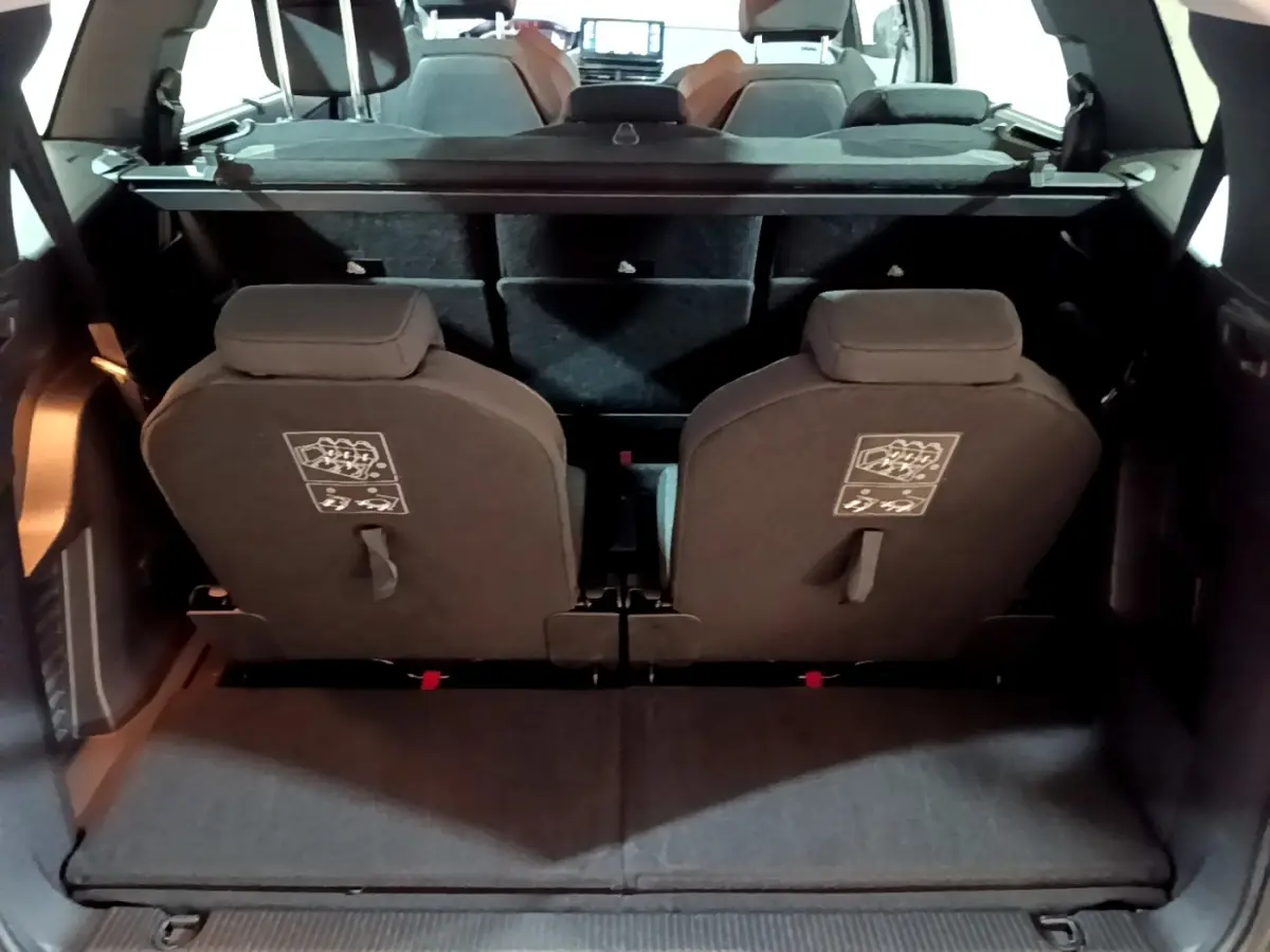 Vue arrière du coffre ouvert du Peugeot 5008 noir, montrant la troisième rangée de sièges individuels rabattus.