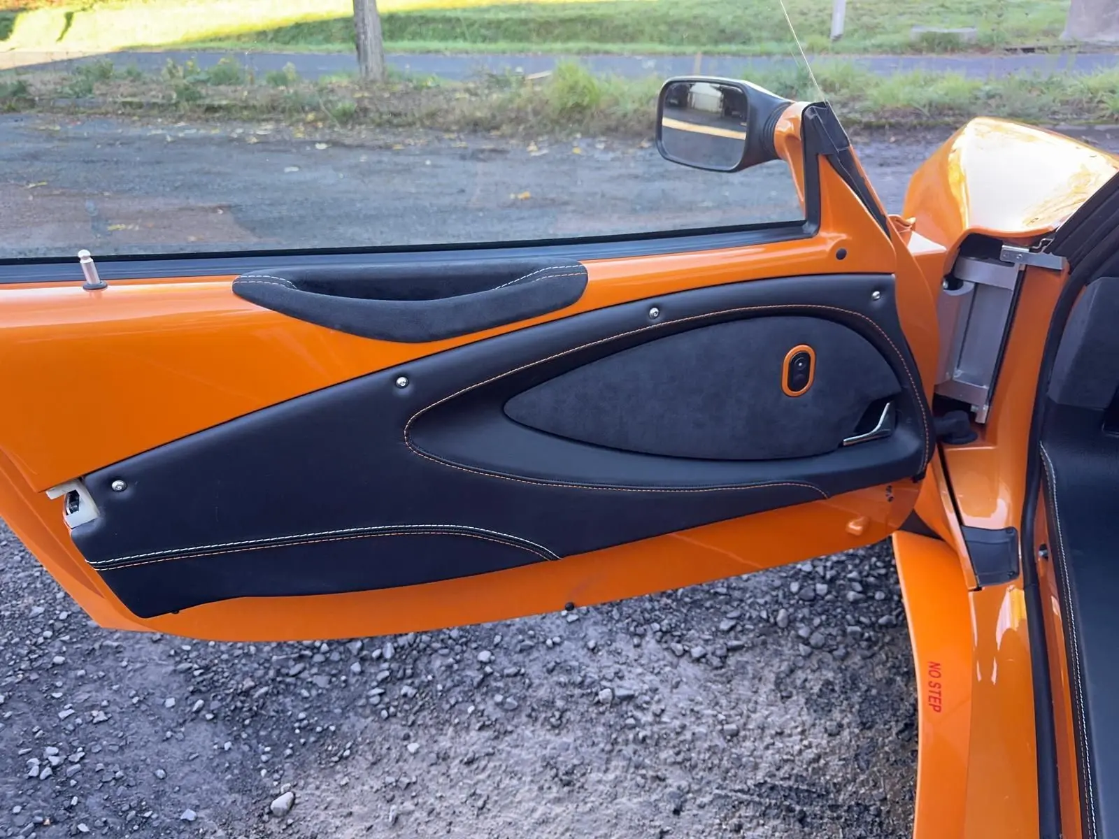 Vue rapprochée de la porte côté gauche orange de la Lotus Elise 3 Cup 250 2021 avec garniture noire et surpiqûres orange.