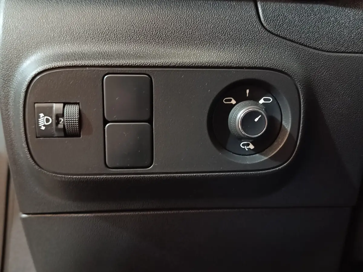 Détail du tableau de bord noir de la Citroën C3 2020, montrant les commandes de réglage des phares et des rétroviseurs.