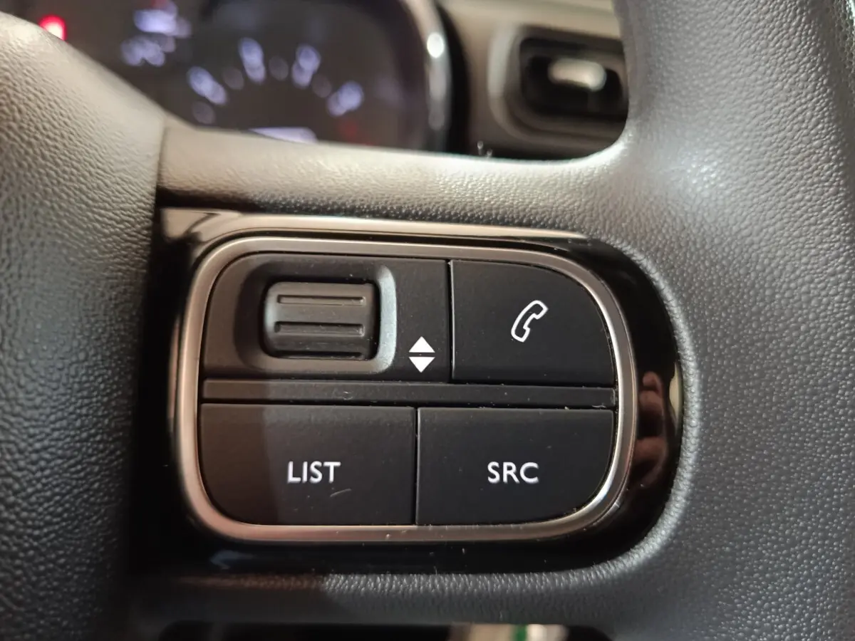 Gros plan sur les commandes multifonctions noires du volant de la Citroën C3 blanche, version Feel Business 2020.