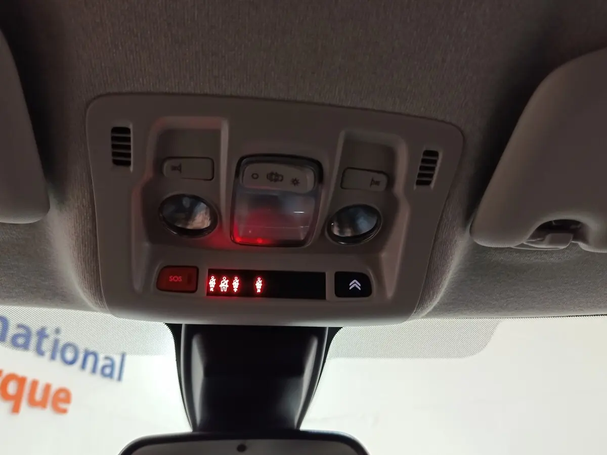 Vue intérieure du plafonnier avec commandes d’éclairage, bouton SOS et indicateurs de ceinture allumés dans une Citroën C3 blanche 2020.