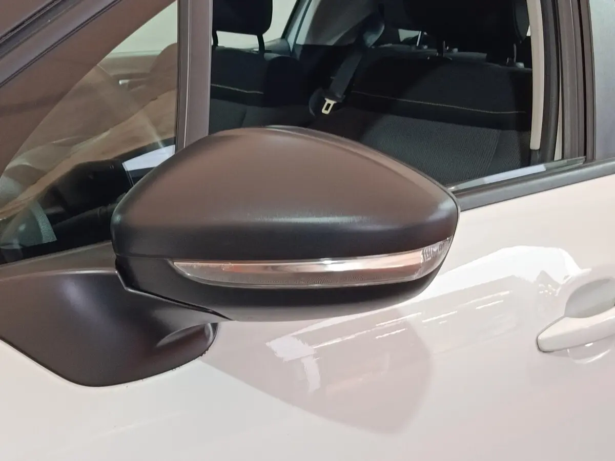 Rétroviseur noir avec clignotant intégré sur porte avant gauche d'une Citroën C3 blanche vue de près.