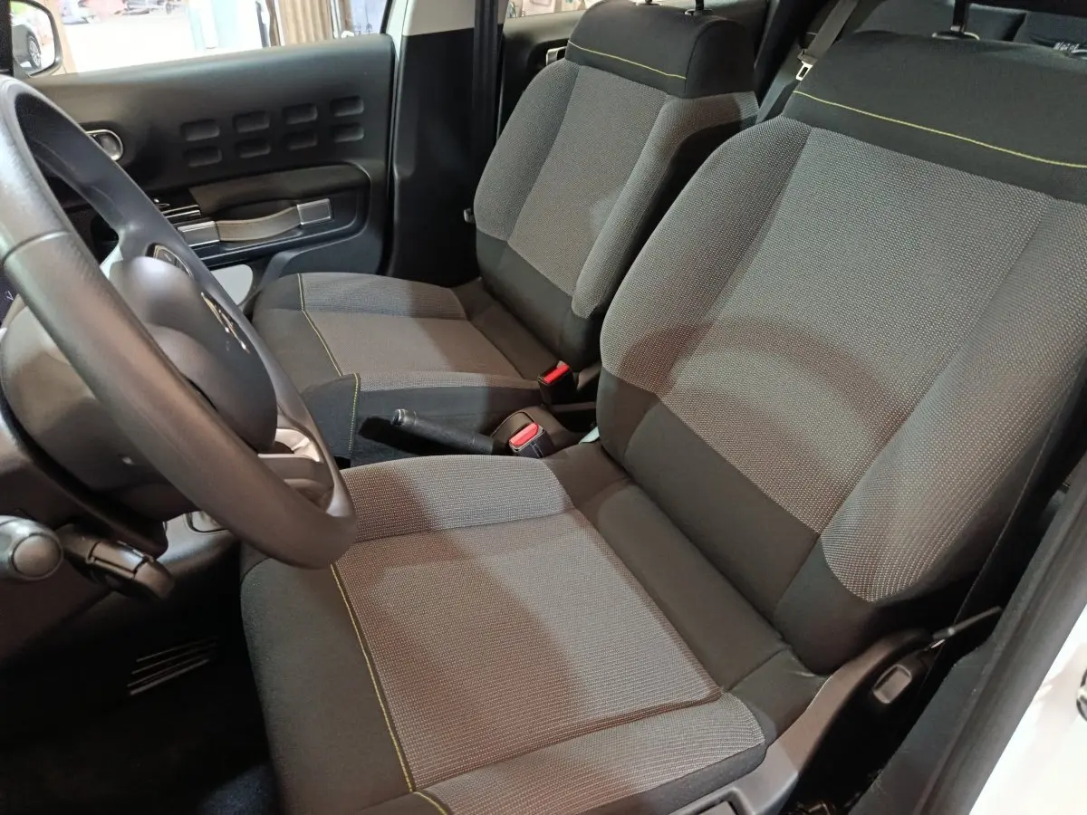Vue intérieure côté conducteur de la Citroën C3 2020, sièges tissu gris avec surpiqûres jaunes et volant multifonctions.