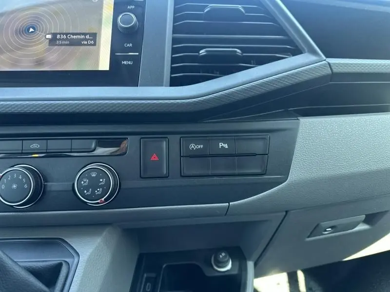 Vue rapprochée de la console centrale du Volkswagen Transporter blanc 2022, avec commandes climatisation et écran tactile.
