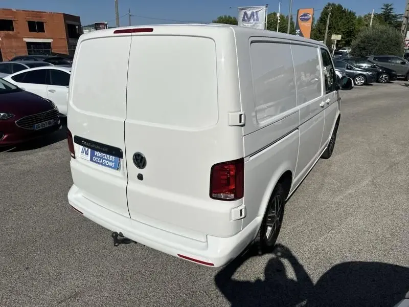 Vue 3/4 arrière droite d'un Volkswagen Transporter blanc 2022, fourgon utilitaire avec hayon double et feux rouges.