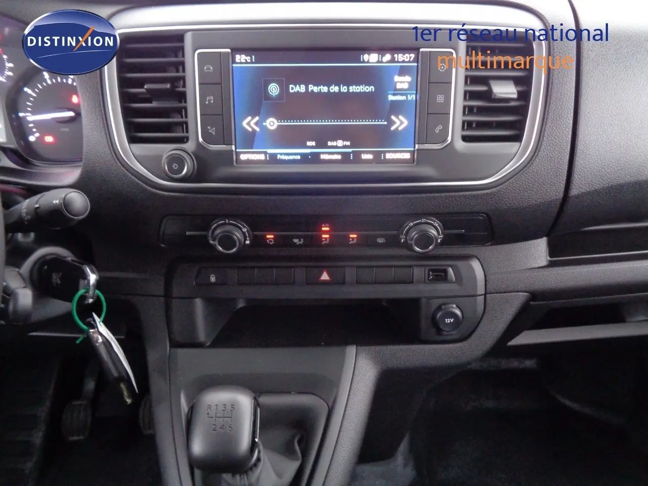 Tableau de bord et console centrale du Peugeot Expert Long 2023 en gris, avec écran tactile et levier de vitesses manuel visible.