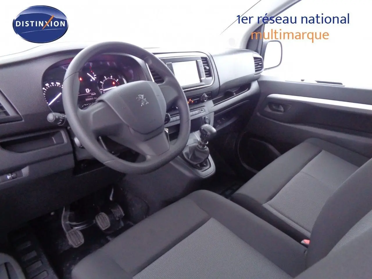 Intérieur du Peugeot Expert Long 2023 vu côté conducteur, avec tableau de bord moderne et sièges noirs en tissu.