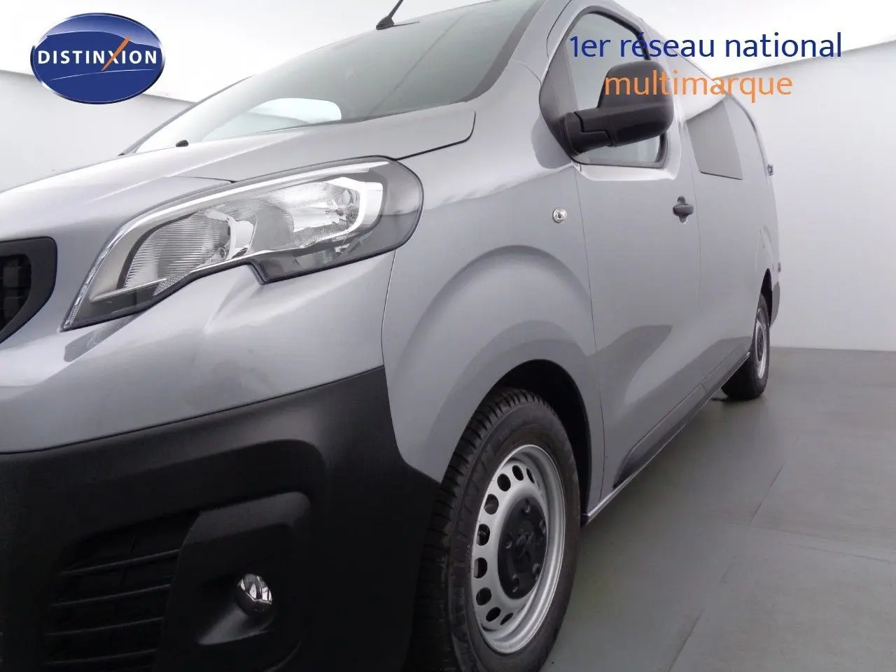 Vue 3/4 avant droit du Peugeot Expert Long gris Artense métal avec pare-chocs noir et jantes acier simples.
