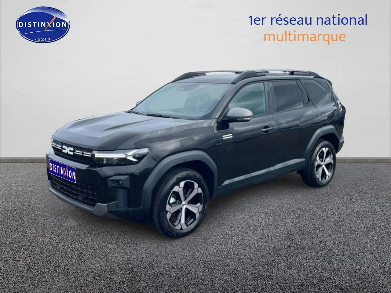 Dacia Bigster 1.8 hybrid noir en 3/4 avant droit, avec jantes alliage diamantées et barres de toit visibles.