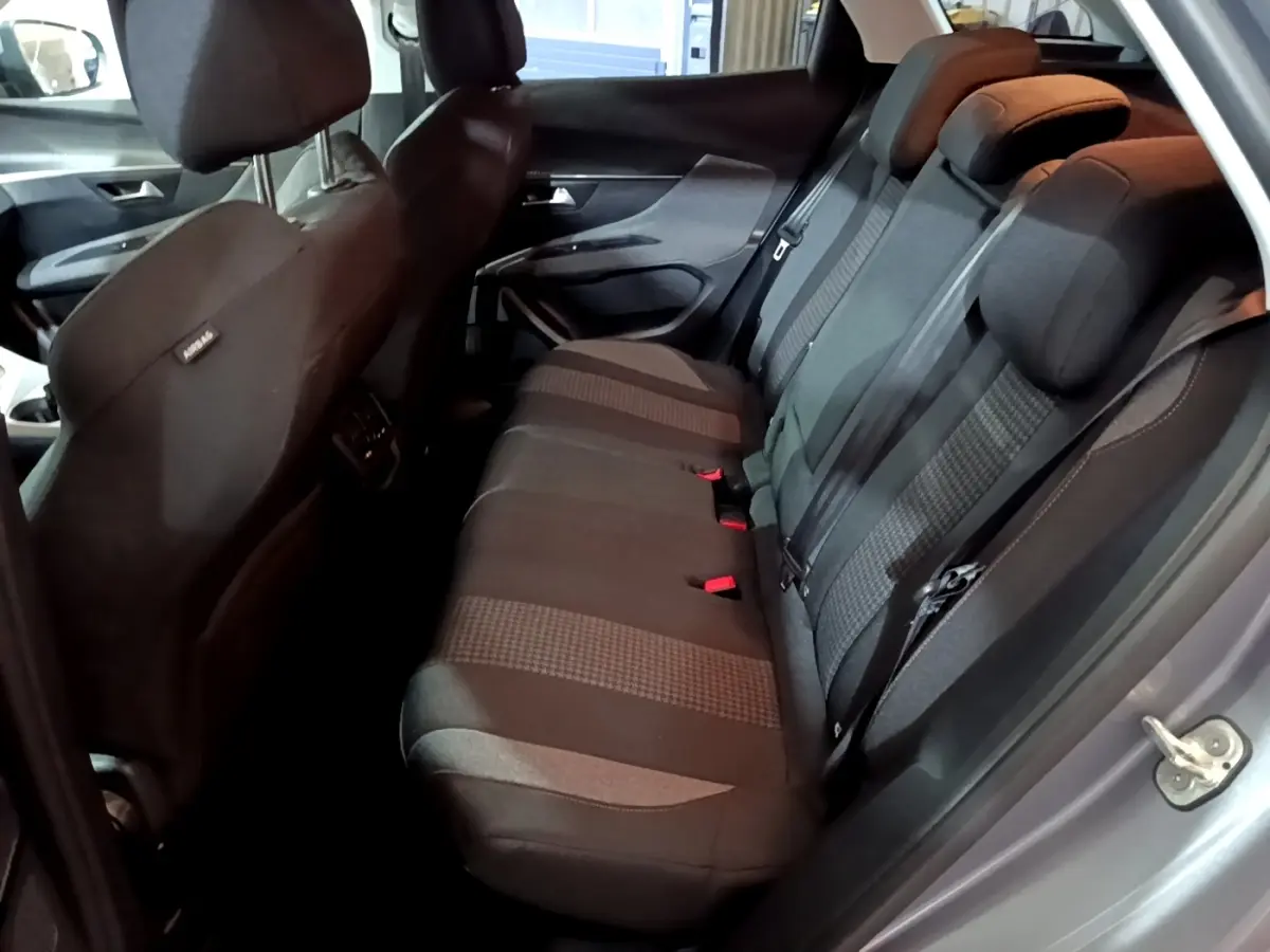 Vue côté droit sur l'intérieur arrière du Peugeot 3008 gris clair, montrant la banquette 3 places en tissu noir.