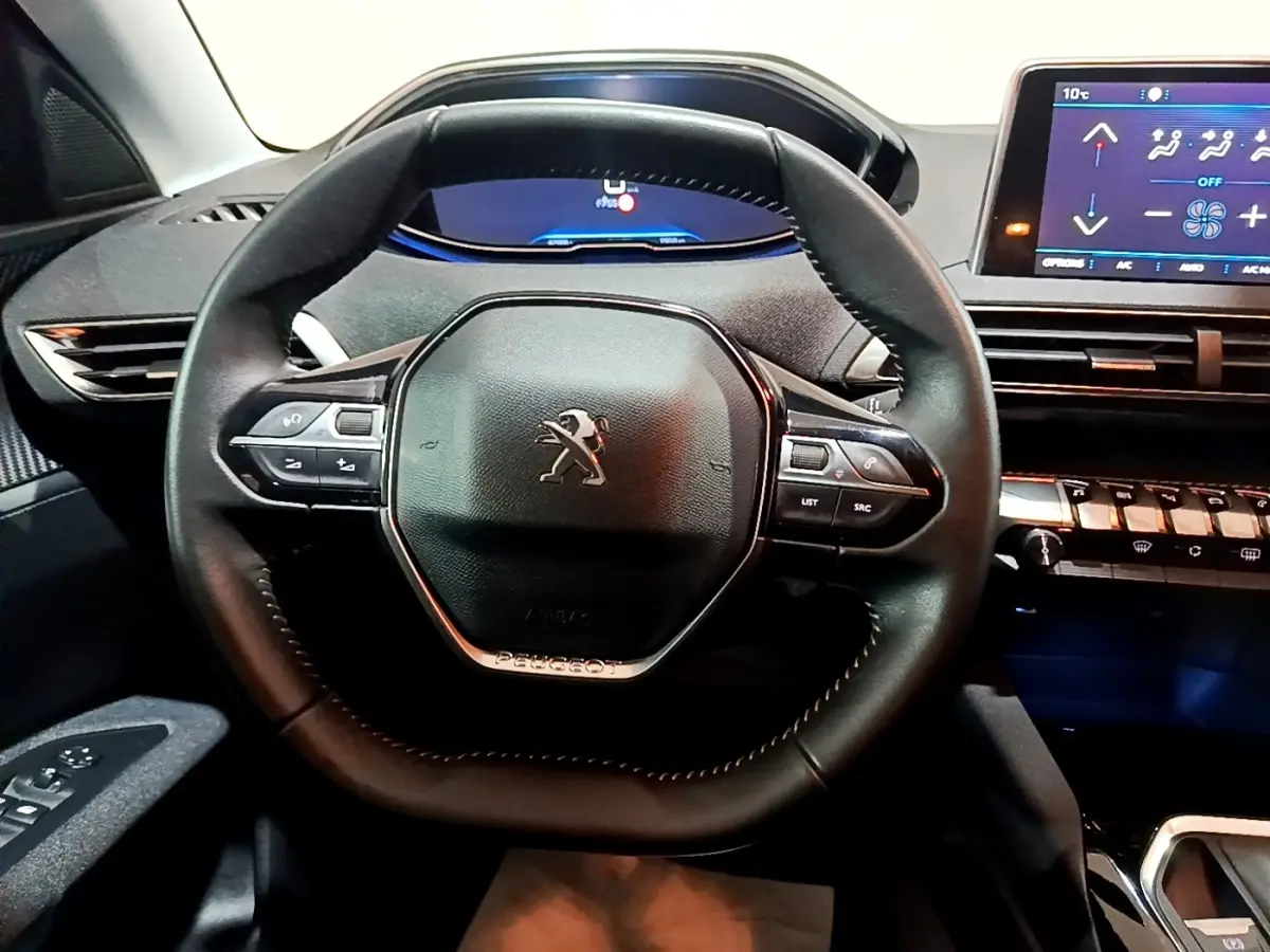 Vue rapprochée du volant cuir noir du Peugeot 3008 avec tableau de bord digital et écran tactile à droite.