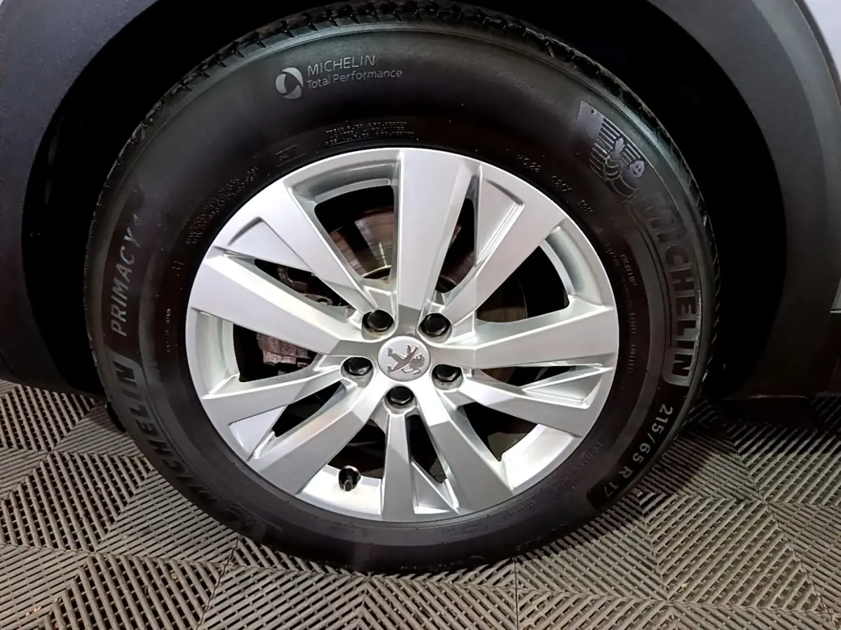 Gros plan sur la roue avant droite d’un Peugeot 3008 gris clair, jante alliage argentée et pneu Michelin.