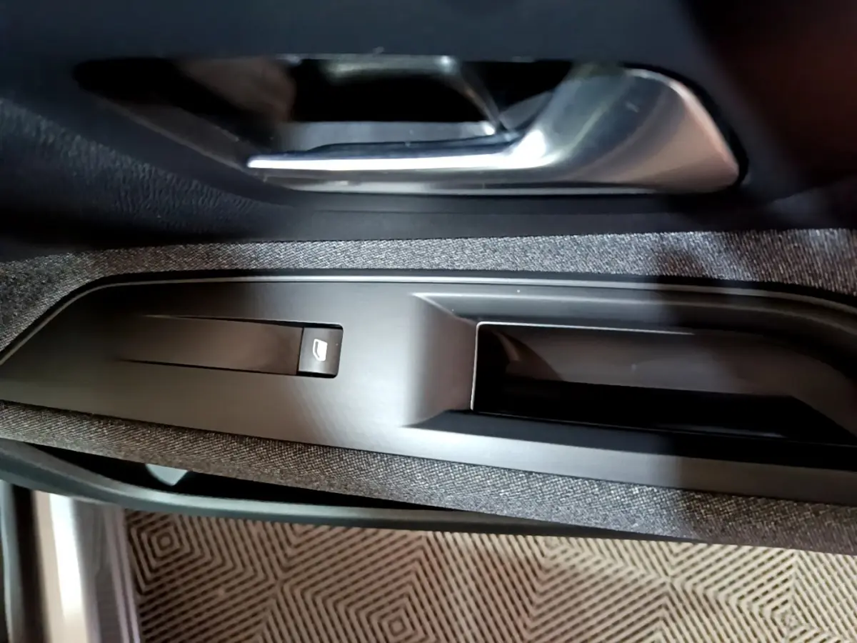 Gros plan sur la poignée intérieure et commande de lève-vitre côté conducteur d’un Peugeot 3008 gris clair 2020.