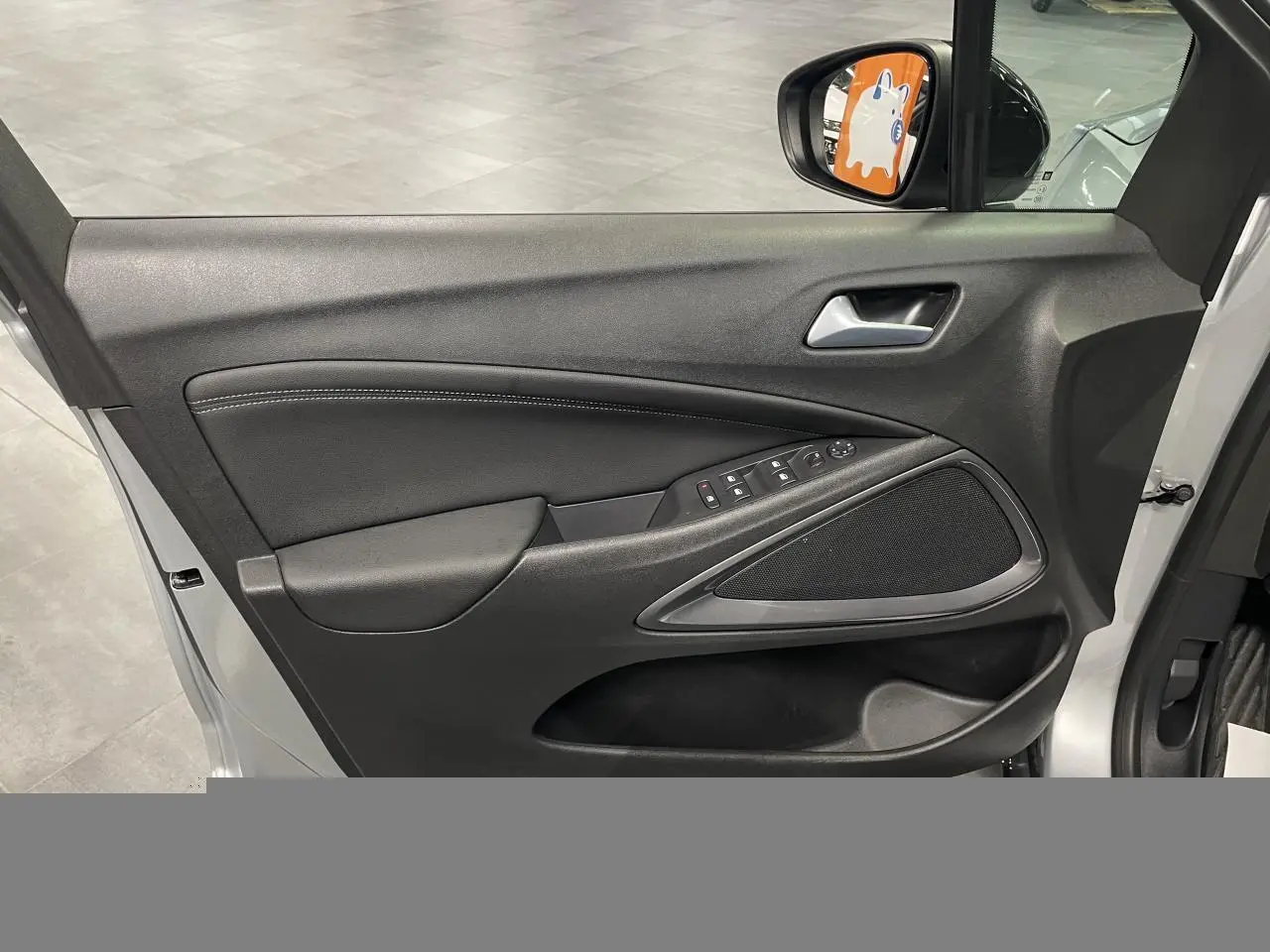 Vue intérieure de la porte avant gauche gris clair de l’Opel Crossland avec commandes électriques et haut-parleur intégré.