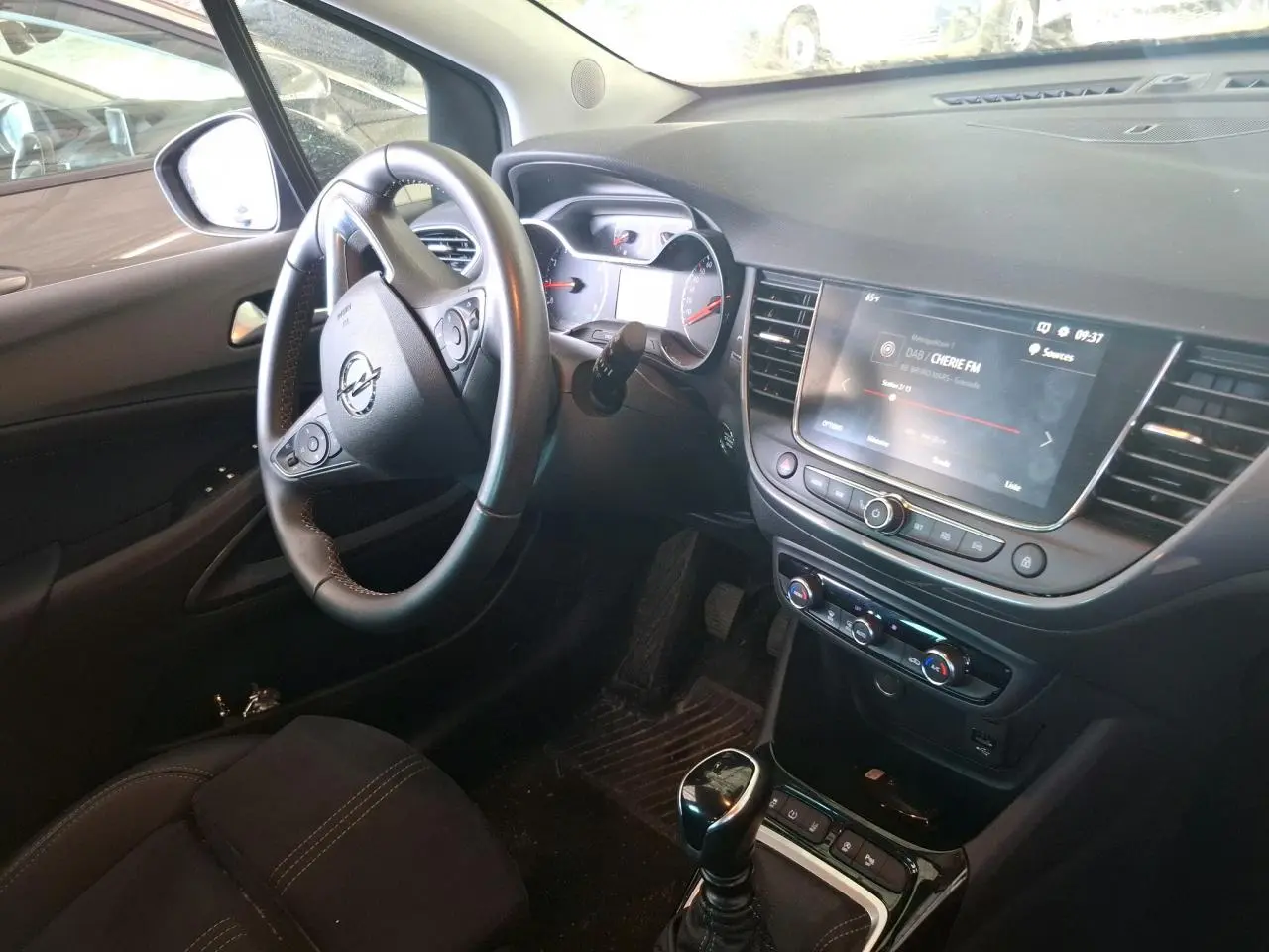 Vue intérieure côté conducteur de l’Opel Crossland gris clair 2024, avec volant multifonction et écran tactile central allumé.