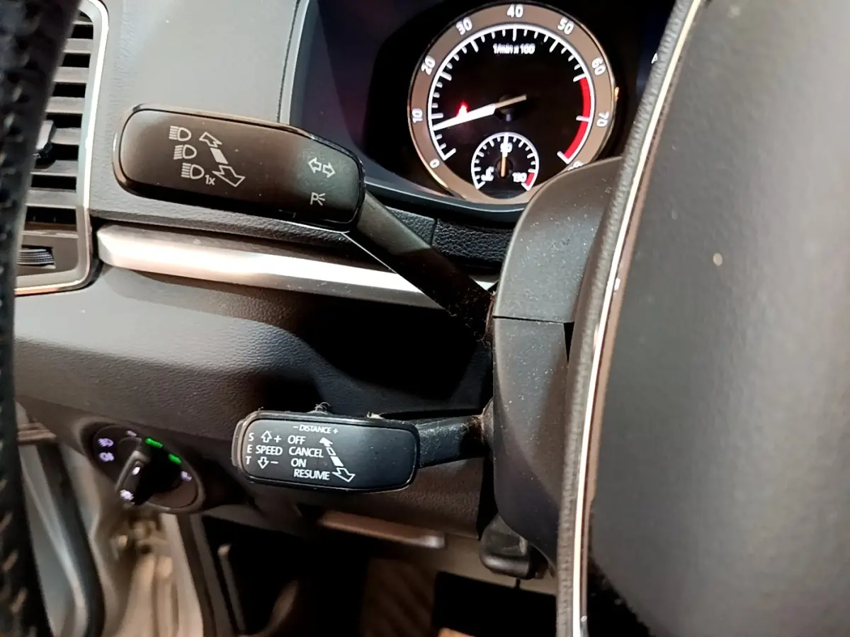 Gros plan sur les commandes au volant et le compteur du Skoda Karoq 1.5 TSI gris clair, tableau de bord intérieur.