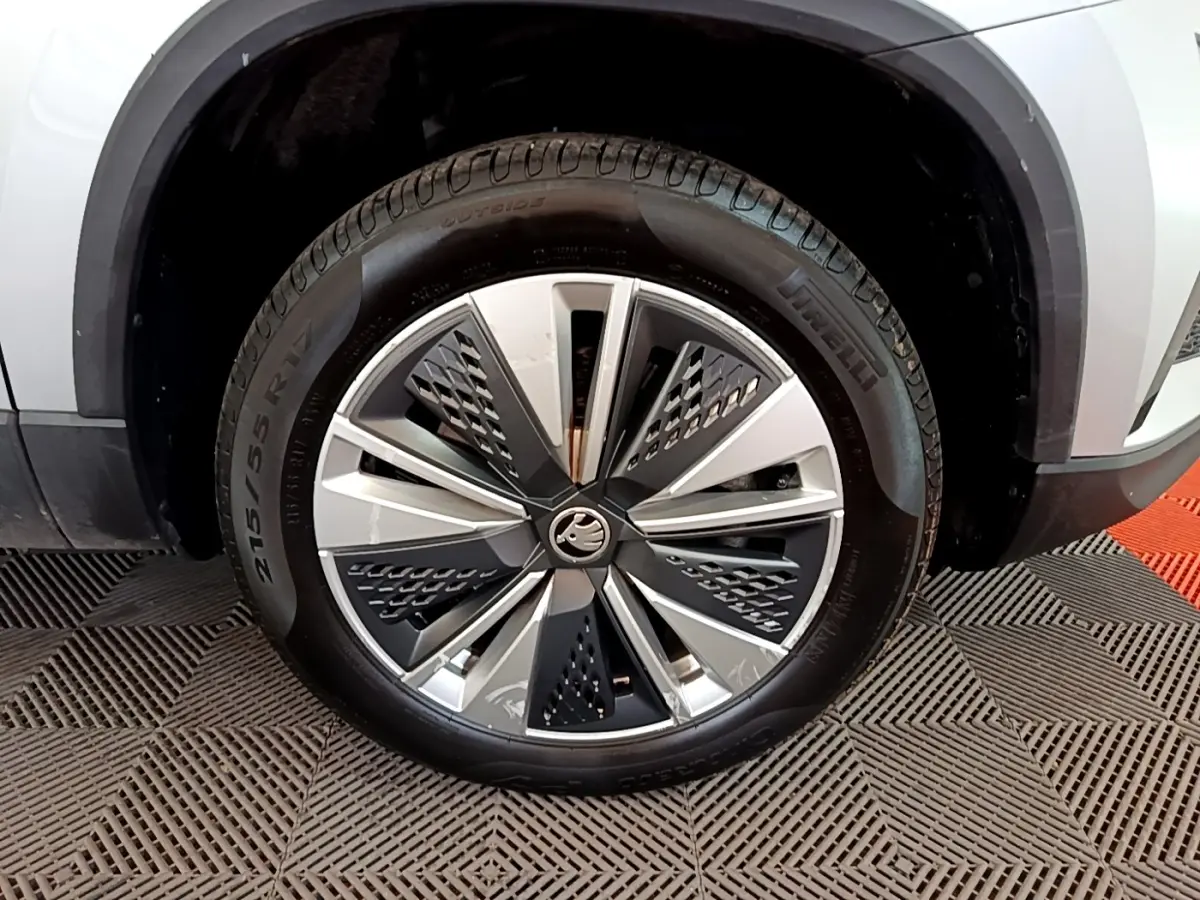 Gros plan sur la roue avant droite d’un Skoda Karoq gris clair avec jante alliage moderne à motifs géométriques.