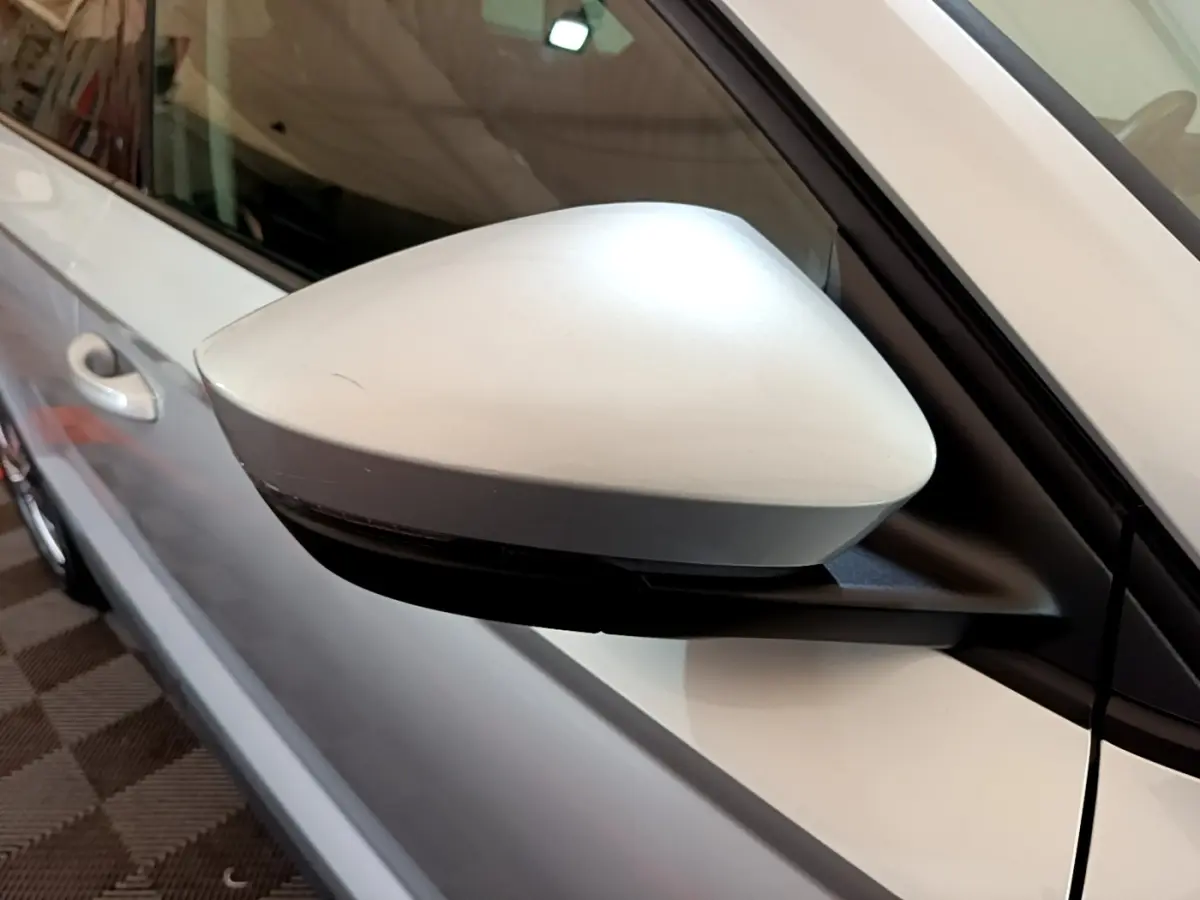 Rétroviseur côté gauche gris clair du Skoda Karoq 2022, avec portière et poignée visibles en arrière-plan.