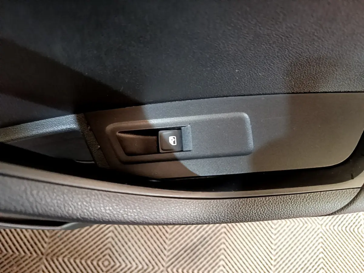 Gros plan sur le bouton d'ouverture du coffre dans l'habitacle noir d'une Skoda Karoq 2022.