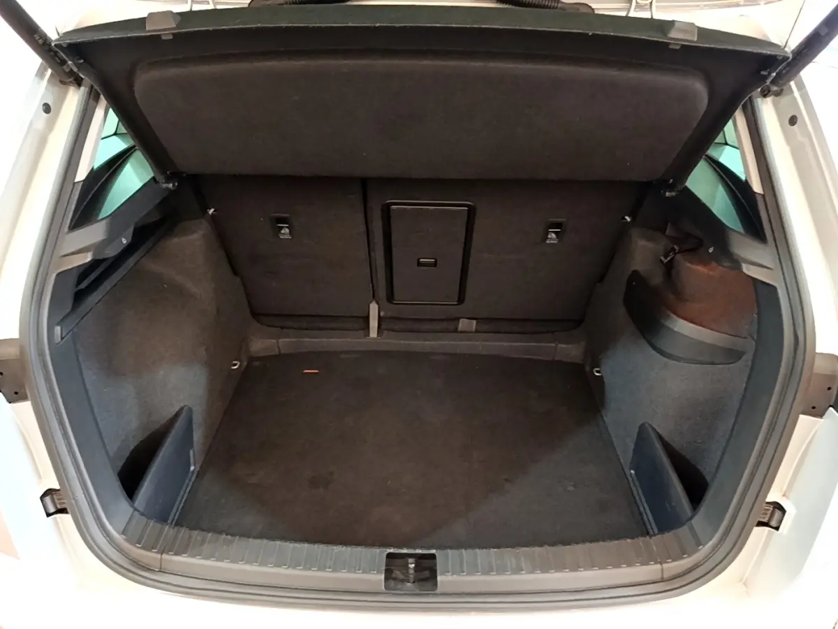 Coffre ouvert vu de l'arrière d'un Skoda Karoq gris clair, montrant un espace de chargement propre et spacieux.