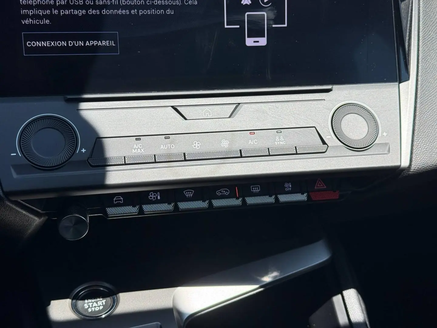 Vue rapprochée de la console centrale de la Peugeot e-308 2025 noire, montrant les commandes climatisation et bouton start/stop.