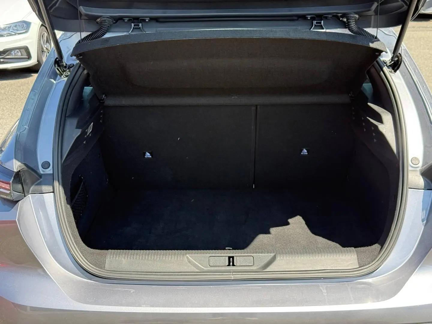 Coffre ouvert vu de l'arrière d'une Peugeot 308 e-308 2025 noir Perla Nera, intérieur noir vide.