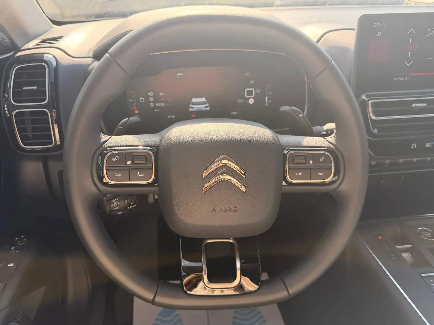 Vue rapprochée du volant cuir multifonction noir du Citroën C5 Aircross 2025 avec tableau de bord digital en arrière-plan.