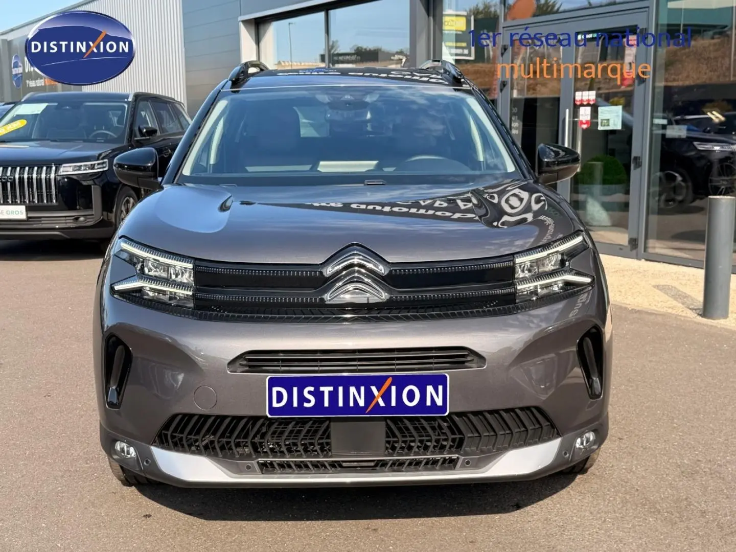 Vue avant d'un Citroën C5 Aircross gris Platinium avec calandre noire et barres de toit visibles.