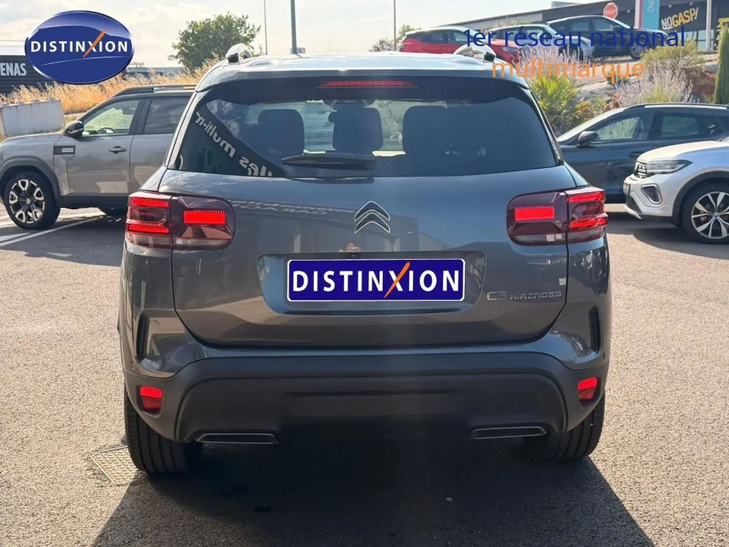 Vue arrière d'un Citroën C5 Aircross gris Platinium avec feux arrière LED et barres de toit visibles.