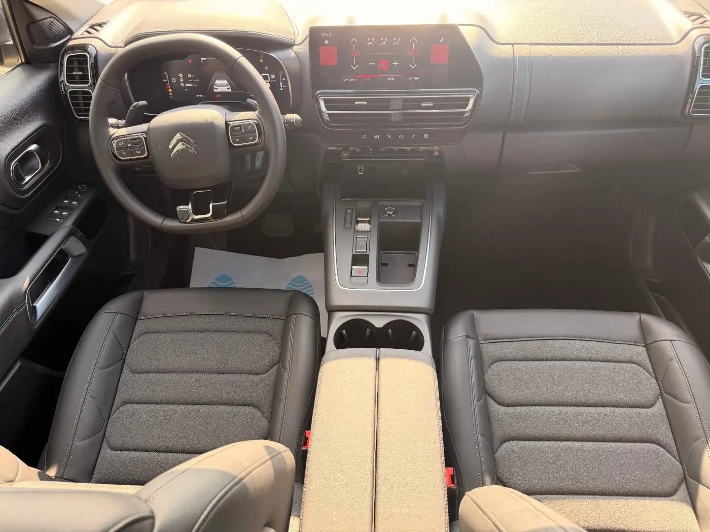 Vue intérieure avant du Citroën C5 Aircross 2025 montrant le volant cuir multifonction et la console centrale avec écran tactile.