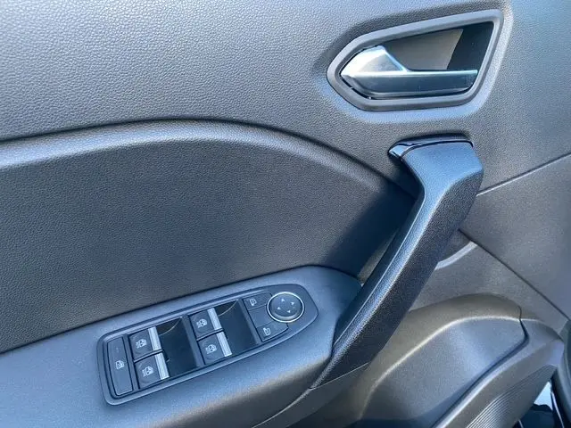 Gros plan sur la poignée intérieure et les commandes des vitres côté conducteur d'un Renault Captur noir, finition tissu noir.
