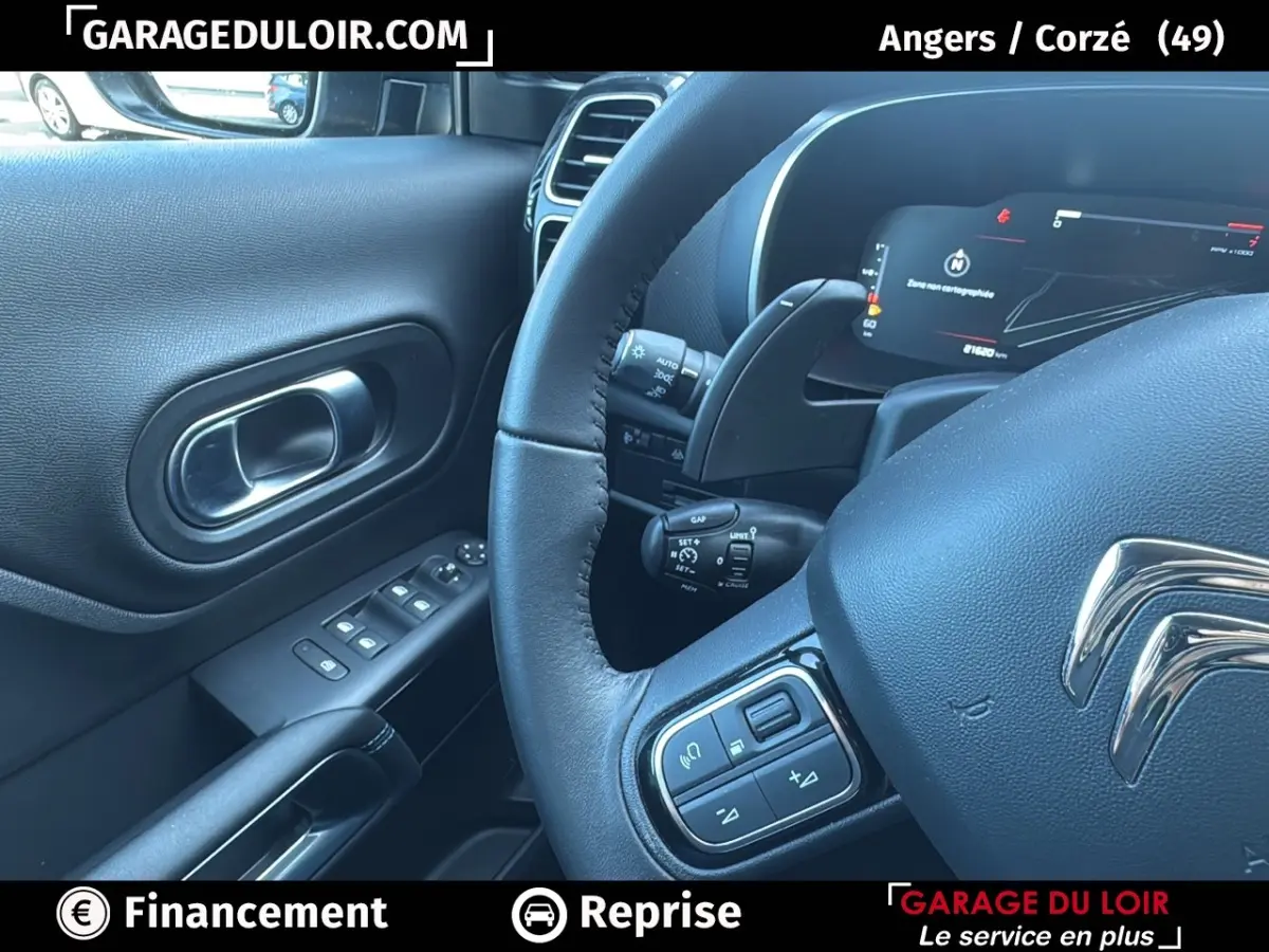 Vue rapprochée du volant cuir et de la porte côté conducteur d’un Citroën C5 Aircross noir, avec commandes intégrées.