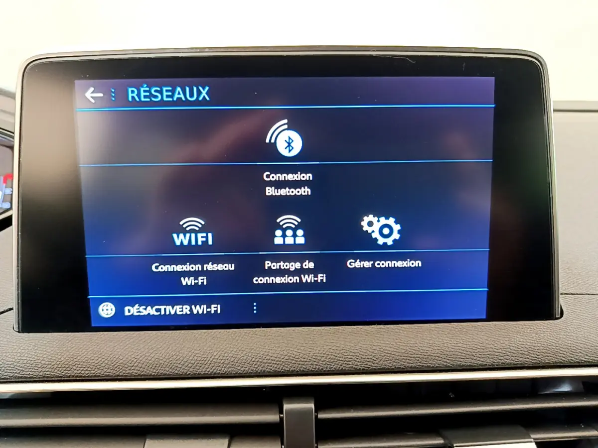Écran tactile central affichant les options réseau Bluetooth et Wi-Fi dans le tableau de bord du Peugeot 3008 gris foncé.