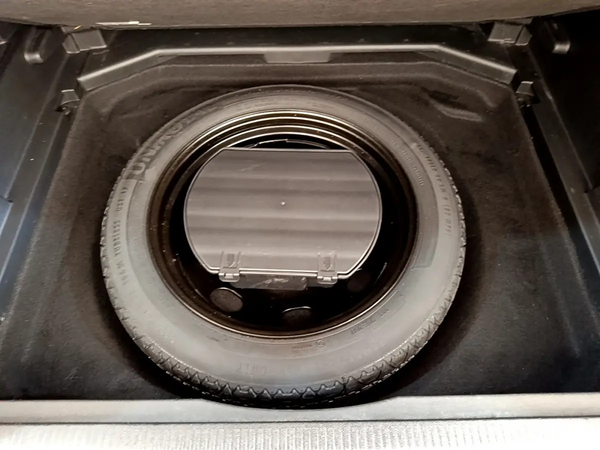 Vue plongeante sur la roue de secours dans le coffre d’un Peugeot 3008 gris foncé de 2020.