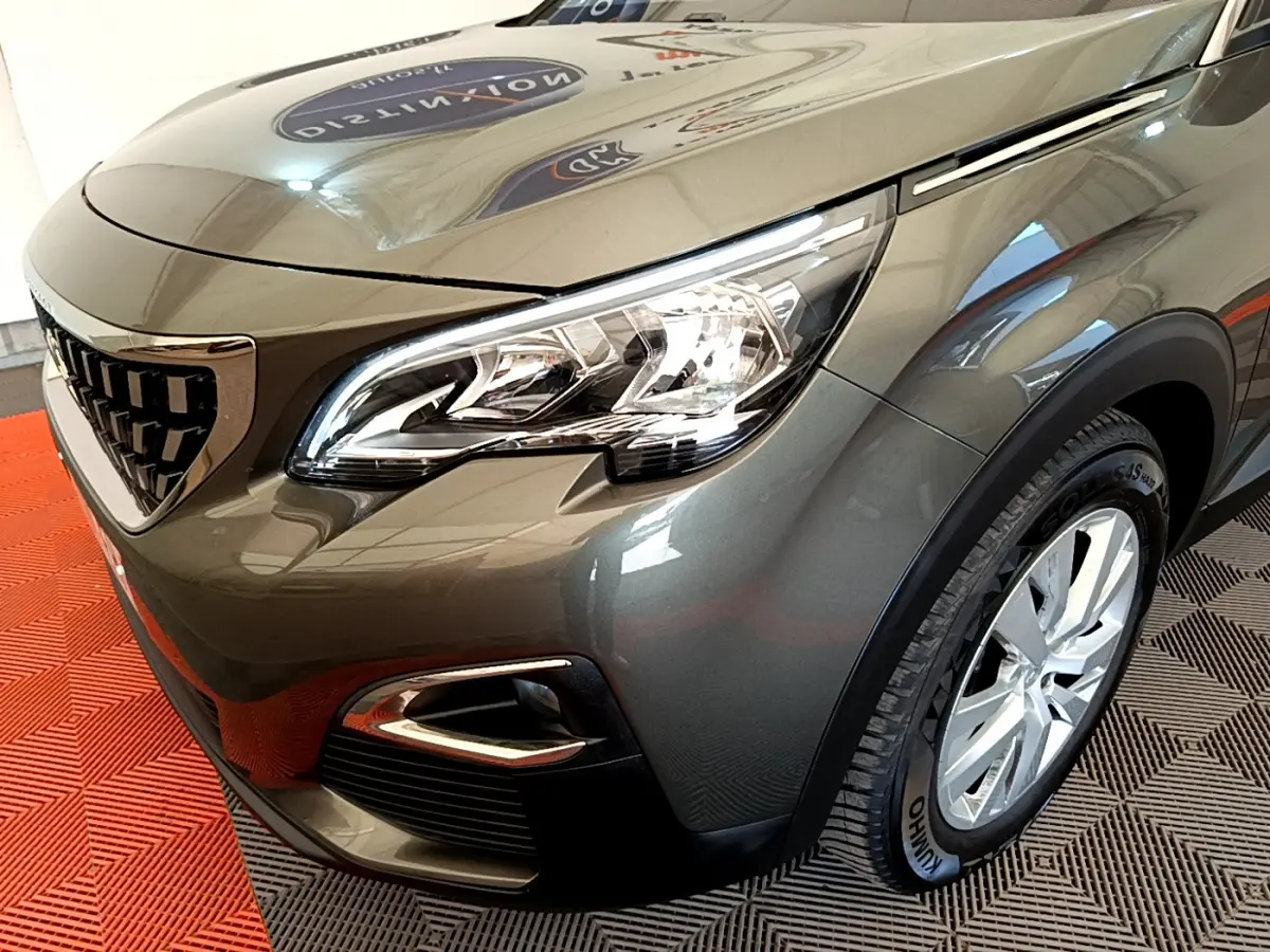 Vue 3/4 avant droit d’un Peugeot 3008 gris foncé mettant en valeur le phare LED et la calandre distinctive.