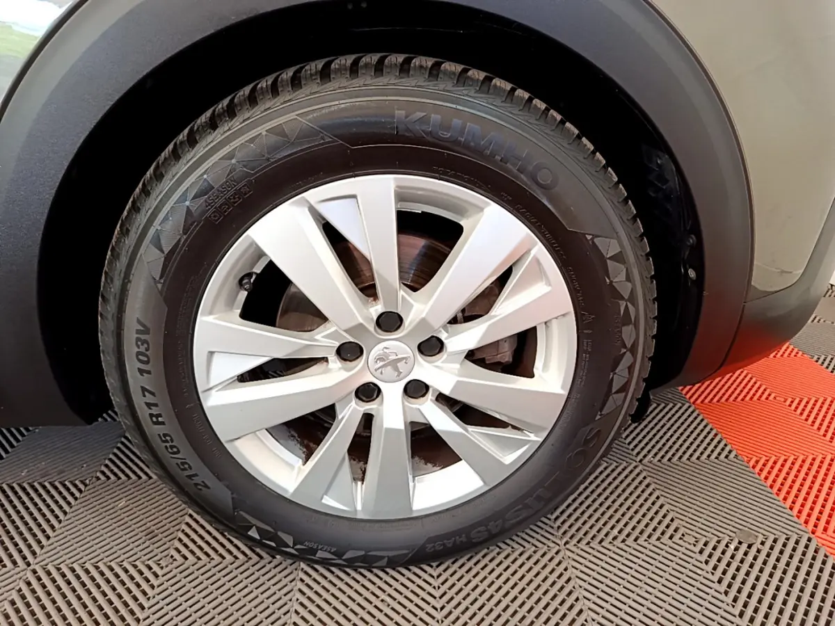 Gros plan sur la roue avant droite d’un Peugeot 3008 gris foncé, mettant en valeur la jante alliage et le pneu Kumho.