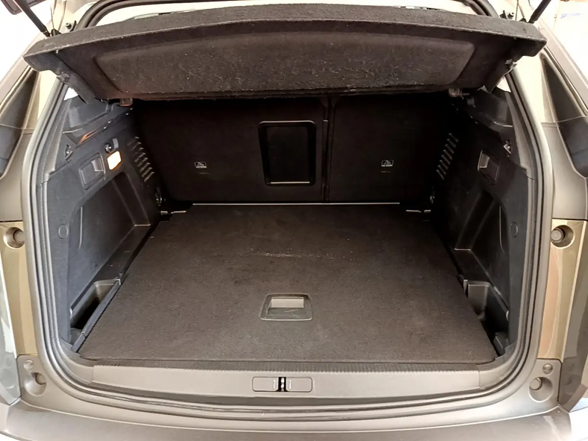 Coffre ouvert vu de l'arrière d'un Peugeot 3008 gris foncé, montrant un espace de chargement propre et spacieux.