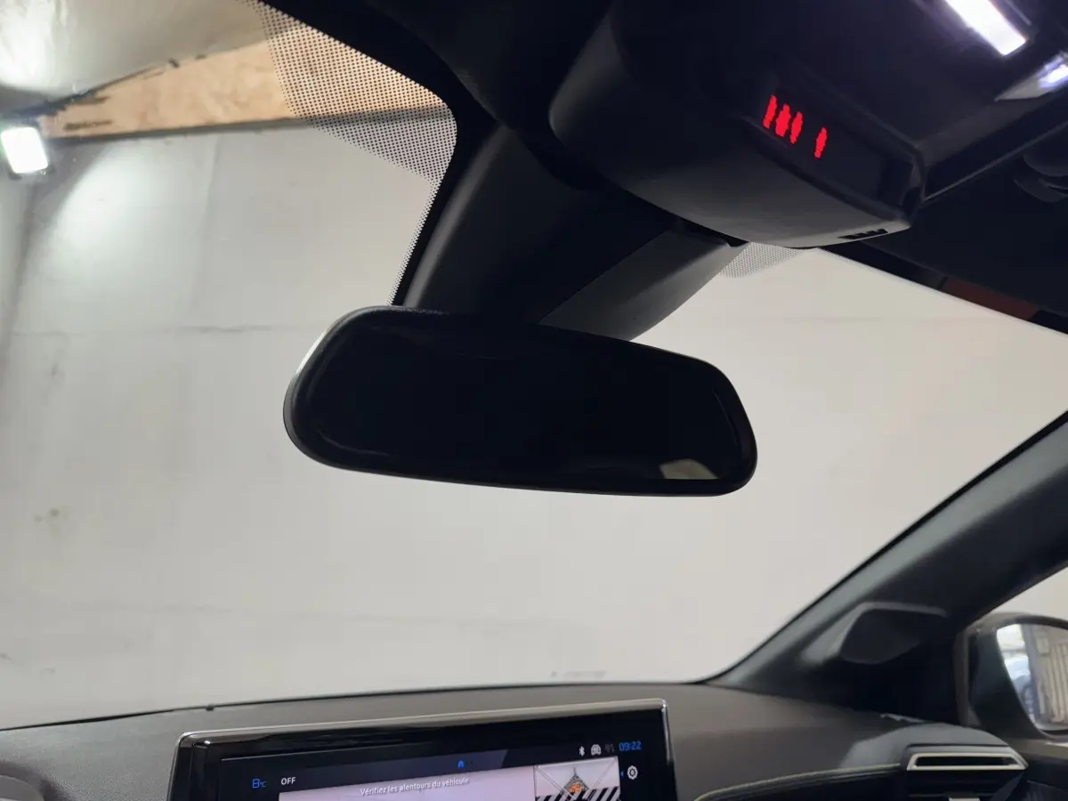 Vue intérieure centrée sur le rétroviseur et l’écran tactile du tableau de bord d’une Peugeot 208 Hybrid gris clair.