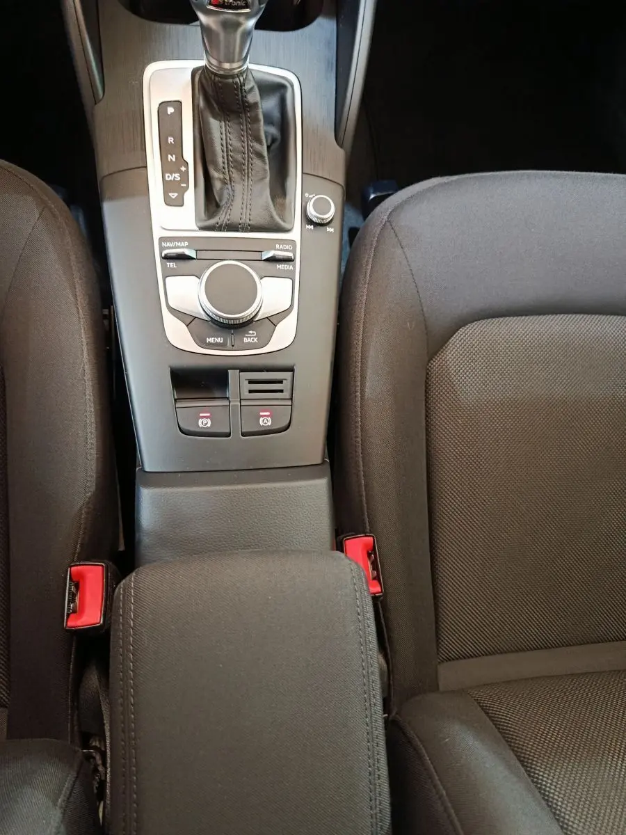 Vue plongeante sur la console centrale noire de l’Audi A3 35 TDI 150 S tronic avec levier de vitesse et accoudoir tissu.