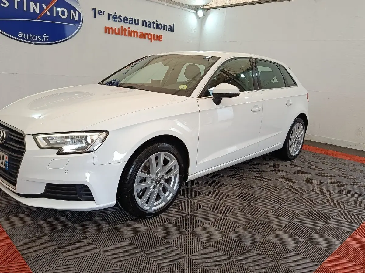 Audi A3 blanc vue 3/4 avant droit, avec jantes alliage et phares LED dans un showroom intérieur.