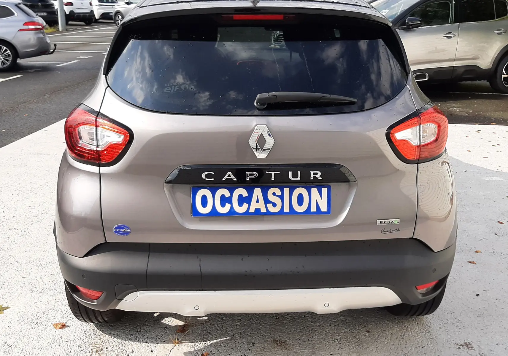 Vue arrière d'un Renault Captur gris Cassiopée avec toit noir, plaque "OCCASION" et feux arrière allumés.